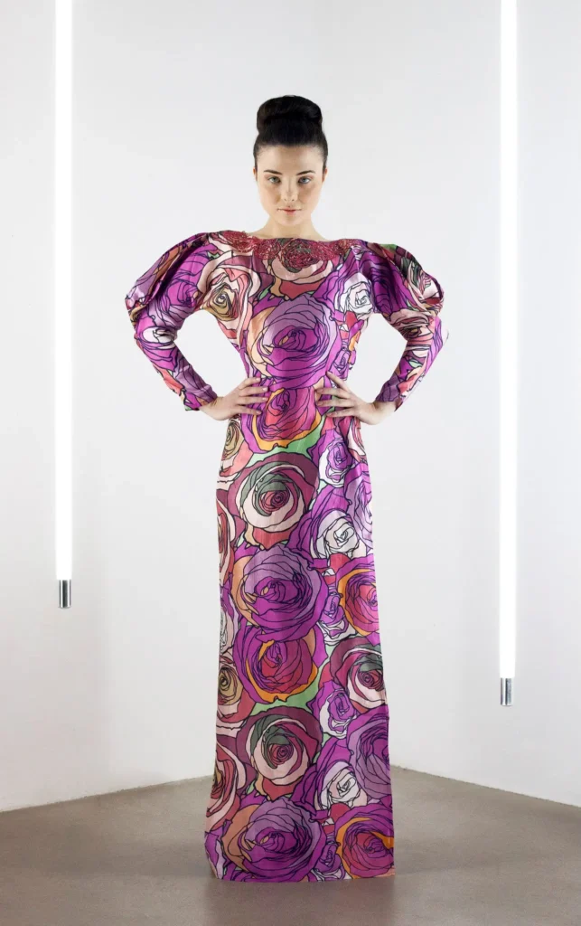 odel wearing a full-length thobe-style dress in red rose print silk satin with exaggerated leg-of-mutton sleeves.